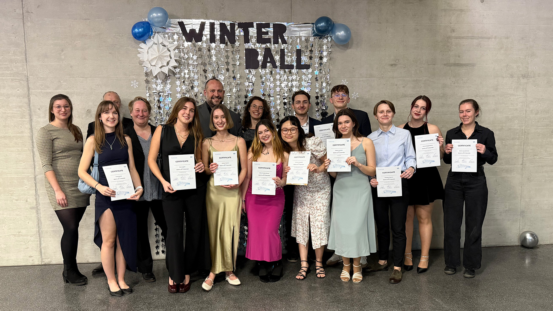 A group of students in festive dresses displaying their awards
