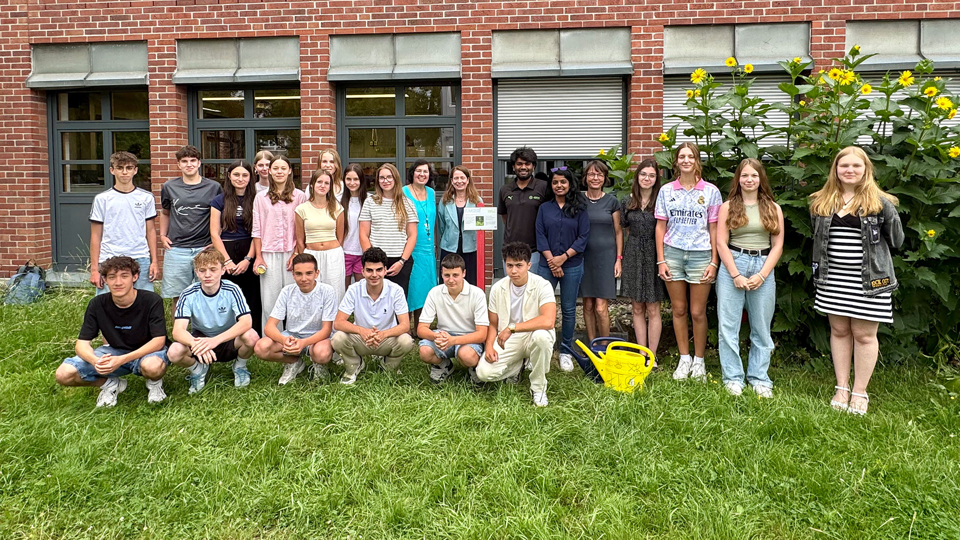 A group shot of a school class in front of a brick house