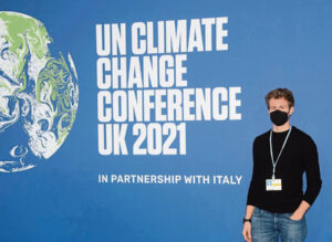 Man mit Maske vor einen Banner: UN Climate Change Conference UK 2021