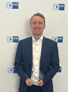 Marco Gruber präsentiert stolz seinen gläsernen IHK-Pokal