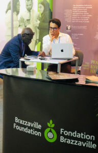 Two men sitting at an information booth on a conference.